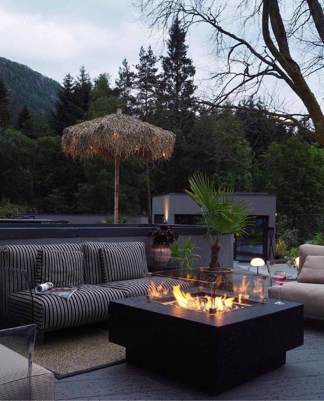 a fire pit with a fire pit and a fire pit with trees and mountains in the background